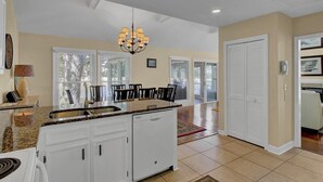 A spacious kitchen with a granite countertop, white cabinetry, and a chandelier. - 15 Lake Village Lane by AvantStay | Golf Course & Lagoon Views (Isle Of Palms)