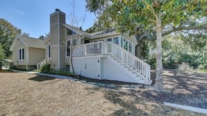 A two-story house with a covered porch and a staircase leading to a deck. - 15 Lake Village Lane by AvantStay | Golf Course & Lagoon Views (Isle Of Palms)