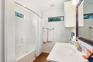 Un baño con bañera, lavamanos, espejo y ventana.