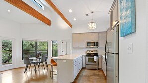 A modern kitchen with white cabinetry, stainless steel appliances, and a large island with bar stools.