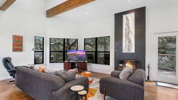 A modern living room with a fireplace, large windows, and a cozy seating area.