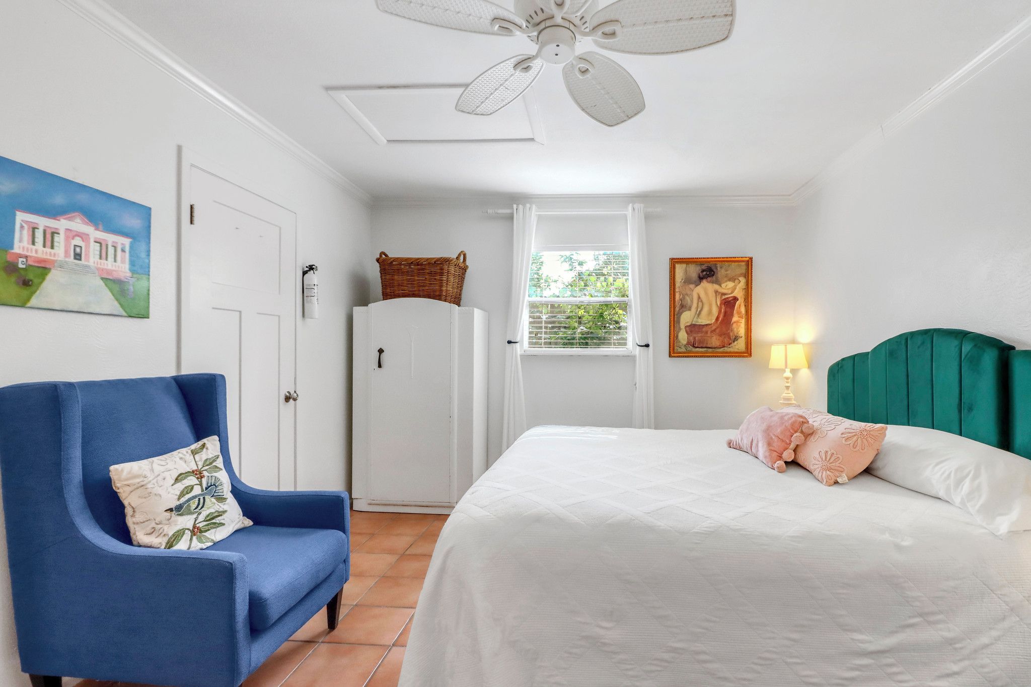 A bedroom with a bed, a chair, a wardrobe, a ceiling fan, a window, and a painting.