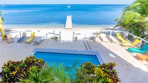 A pool area with lounge chairs and a view of the ocean. - 2 bedroom beachfront in West End with amazing sunset view (Roatan)