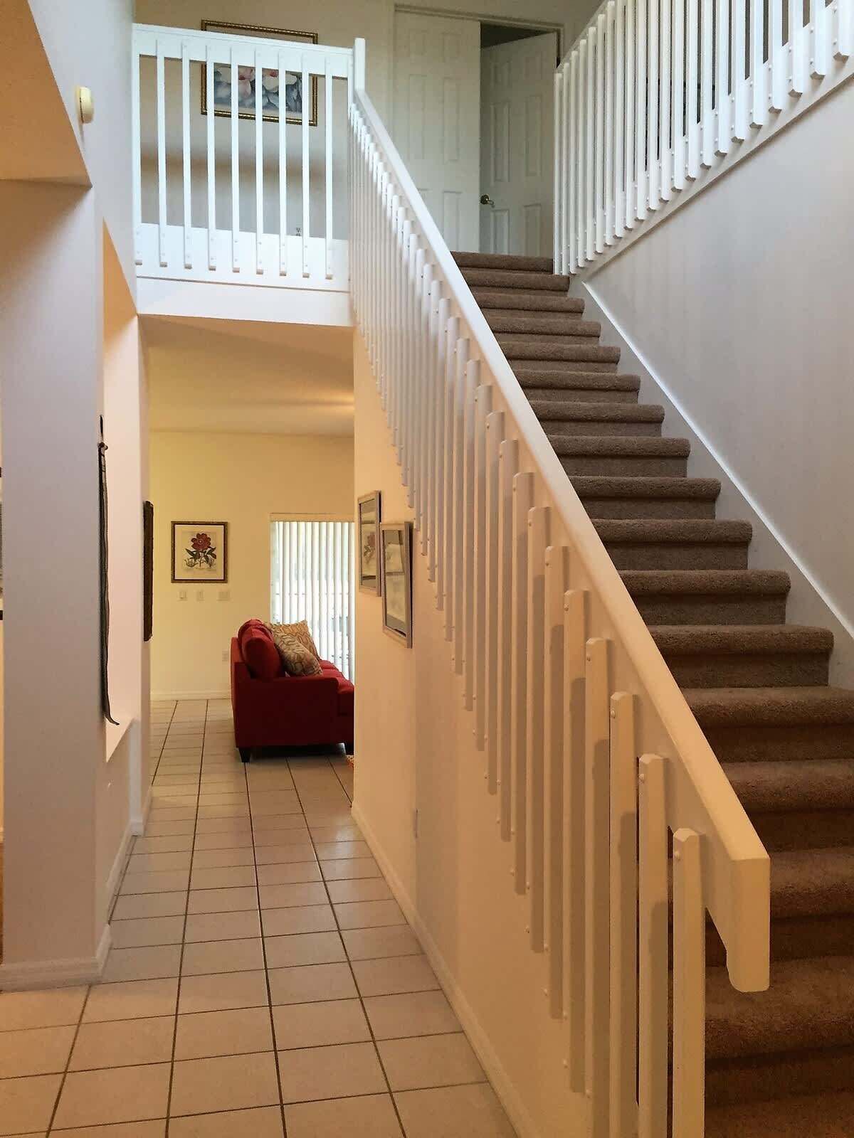 A staircase with a white railing leading to a second floor.