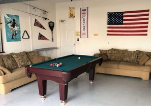 A room with a pool table, two sofas, and various sports memorabilia on the walls. - Lakefront Pool Villa w/ Game Room, Near Disney (Kissimmee)