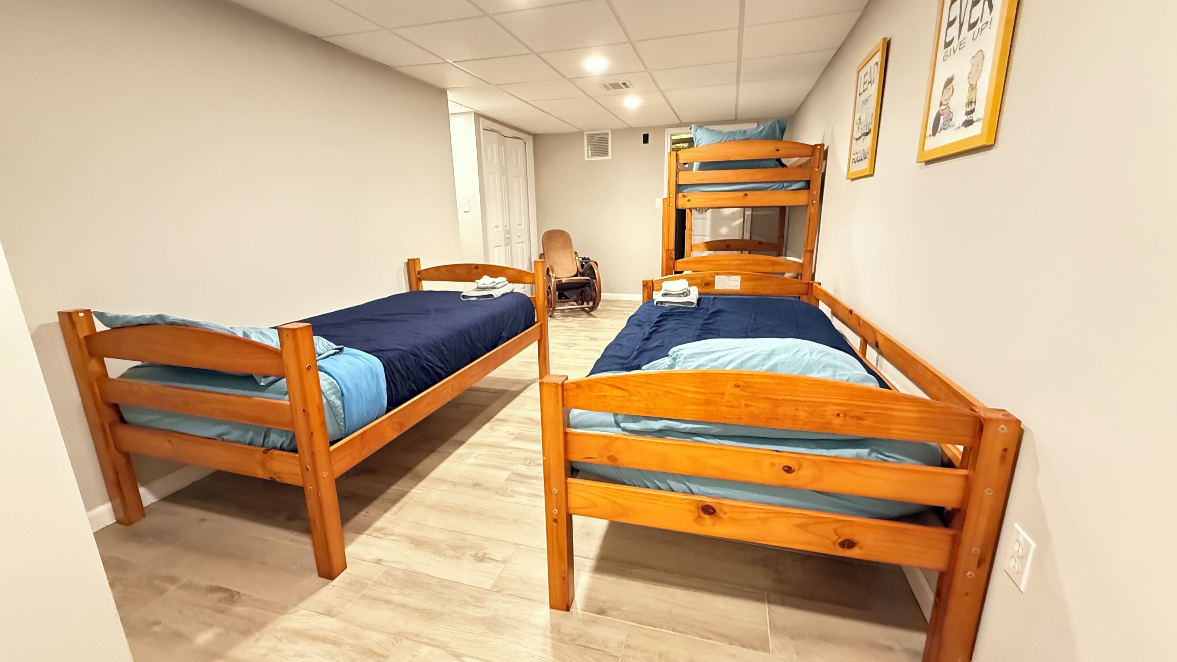 A room with two wooden bunk beds, a chair, and a door.