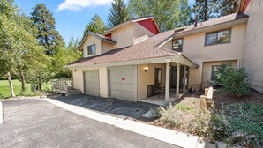 A two-story house with a garage, a covered porch, and a well-maintained lawn.