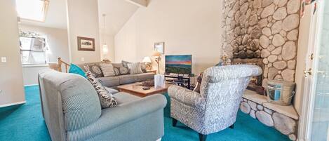 A cozy living room with a stone wall, a sofa, a patterned armchair, and a painting.