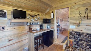 A cozy cabin interior with a wooden interior, a kitchenette, a television, and a patterned rug. - W-W: Guest Ranch Group Lodging up to 70! (Monticello)
