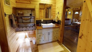 A wooden cabin bathroom with a sink, mirror, and towel storage. - W-W: Guest Ranch Group Lodging up to 70! (Monticello)