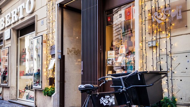Una bicicleta con un cesto estacionada frente a un edificio con un letrero que dice "BERTO".