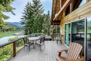 Enjoy a serene outdoor space with a round table and chairs, overlooking a lake and forest.