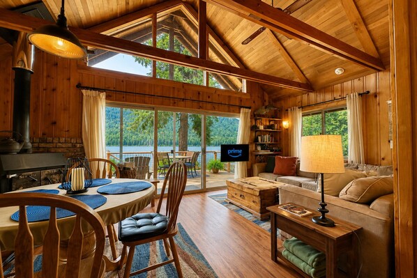 Eine Hütte mit Essbereich, einer Couch, einem Fernseher und einem Kamin.