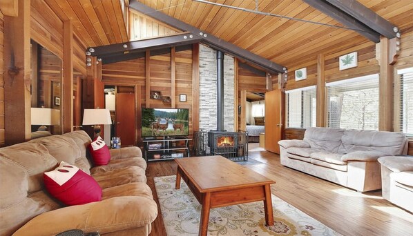 L’intérieur d’une cabane en rondins, avec une cheminée, deux canapés, une table basse et un téléviseur.