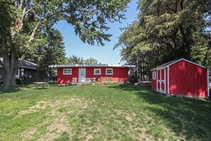 A red single-story house with a front porch and a small shed. - Bluegill Hill Hutchins Lake, Wineries, Breweries! (Fennville)