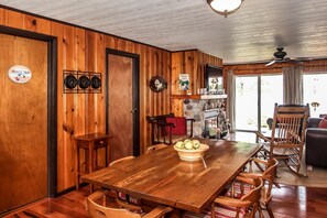 Un interior de madera con una mesa de comedor, sillas, una chimenea y vistas al exterior.