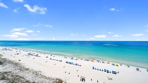 Ein Strand mit weißem Sand, klarem türkisblauem Wasser und blauem Himmel.