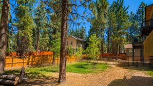 A residential area with a house, a fenced yard, and a building with a balcony. - Fanciful Winter's Lake - Portable AC, Walk to Lake, Close to Village, Fireplace, Barbecue (Big Bear Lake)