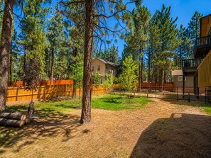 A residential area with a house, a fenced yard, and a building with a balcony. - Fanciful Winter's Lake - Portable AC, Walk to Lake, Close to Village, Fireplace, Barbecue (Big Bear Lake)
