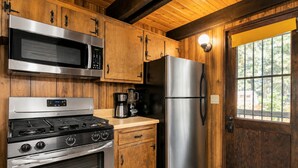 A kitchen with wooden cabinets, stainless steel appliances, a stove, oven, microwave, and refrigerator. - Fanciful Winter's Lake - Portable AC, Walk to Lake, Close to Village, Fireplace, Barbecue (Big Bear Lake)