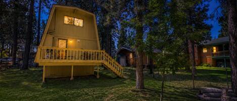 Une cabane avec un toit en pente, un balcon et un escalier menant à l’entrée.