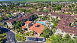 Vista aérea de una zona residencial con varios edificios de apartamentos, una piscina y un estacionamiento.