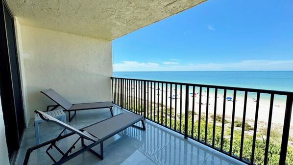 A balcony with two sun loungers and a view of the beach.
