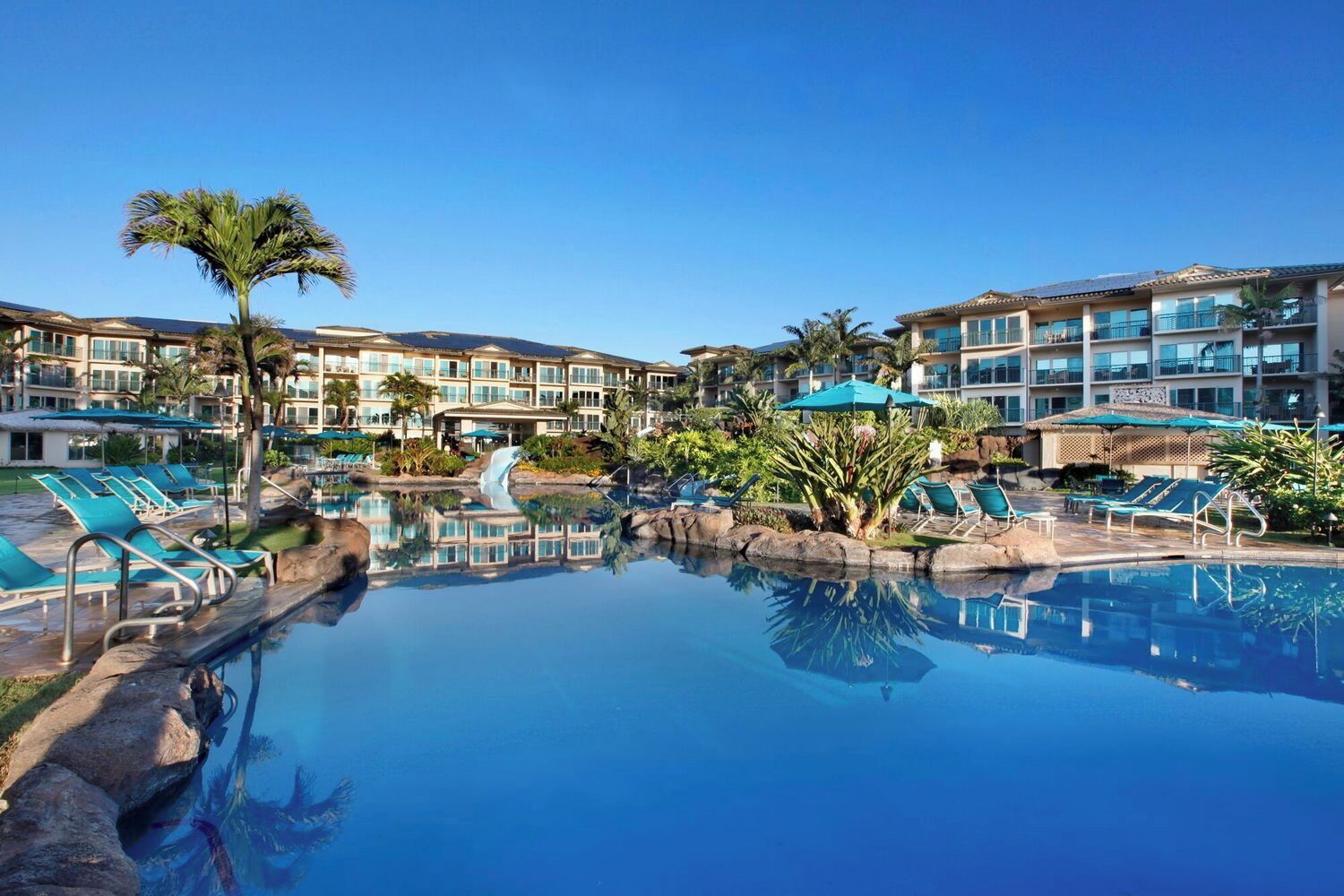Ett semesterhotell med en stor pool, solstolar och ett vattenfall.