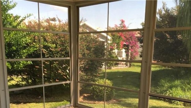 A conservatory with a glass roof, a round table, a cushioned chair, and a wooden bench. - POLO RIDGE NICE RANCH CLOSE TO DINING SHOPPING BANKS AND MORE THE VILLAGES FL (The Villages)