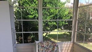 A conservatory with a glass table, floral chair, and a view of a garden. - POLO RIDGE NICE RANCH CLOSE TO DINING SHOPPING BANKS AND MORE THE VILLAGES FL (The Villages)