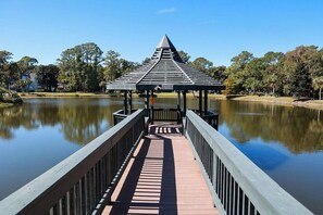 A wooden pier leading to a gazebo with a sloped roof, surrounded by calm water and trees. - Short bike ride to Shipyard Beach Club and on-site (Hilton Head Island)
