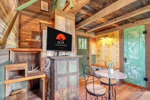 Un interior rústico con techo de madera, un letrero de Hill Country Premier Lodging, una puerta verde y una mesa redonda con sillas.