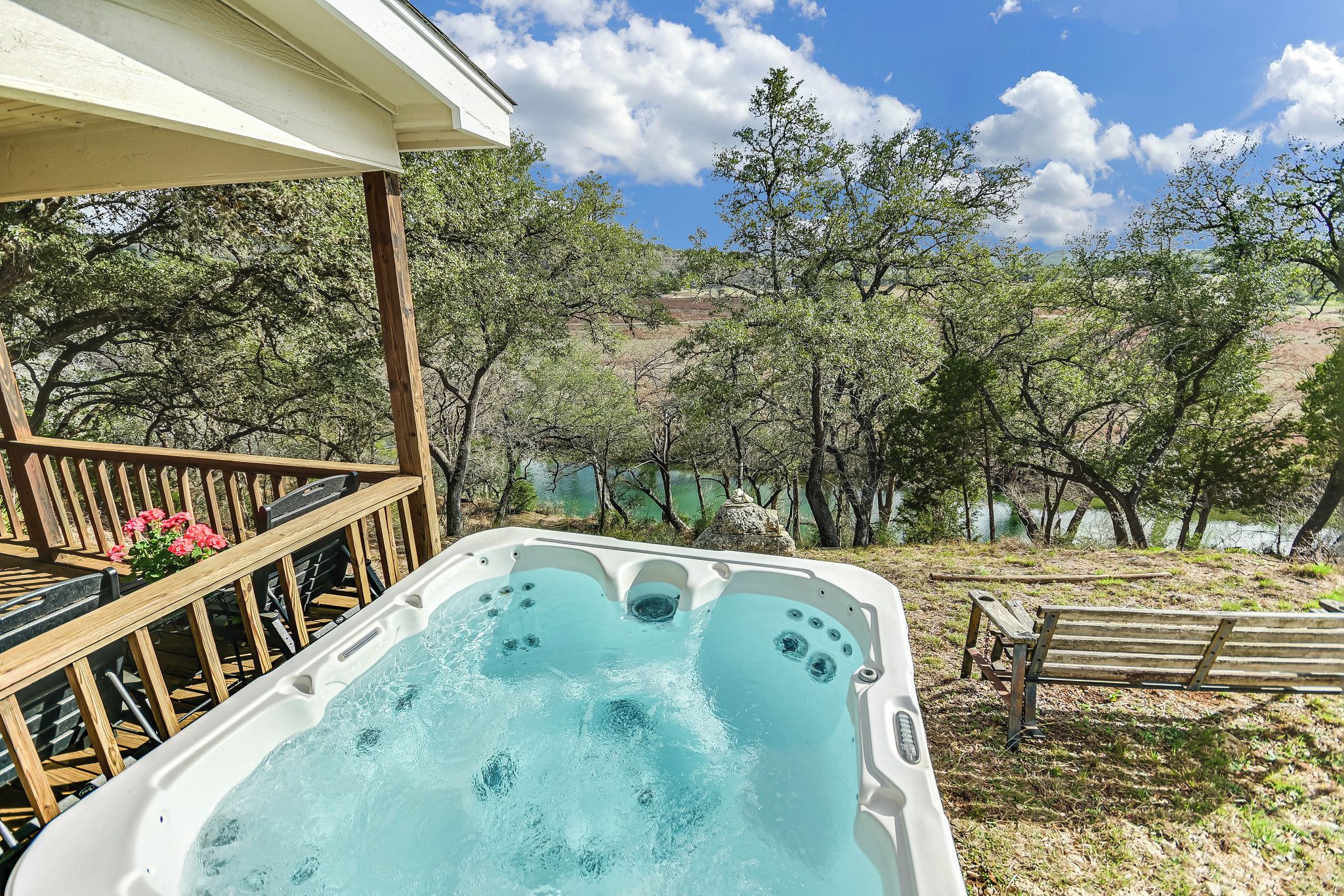 A hot tub on a wooden deck with a view of trees and hills.