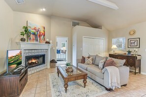 A living room with a fireplace, a sofa, a coffee table, and a television. - Beautiful views and the Crystal Clear waters of the Blanco River await you! (Wimberley)