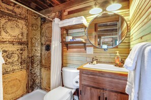 Un baño rústico con tocador de madera, un espejo redondo y un inodoro.