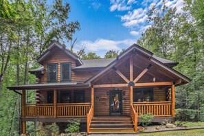 Step into this charming cabin, featuring a cozy porch and a steeply pitched roof.