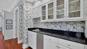Cocina con armarios blancos, encimera negra y salpicadero con motivo de pájaros.