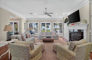 A spacious living room with a fireplace, comfortable seating, and large windows offering a view.