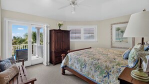 Un dormitorio con cama, ventilador de techo, ventana con persianas, un armario y vistas al exterior.