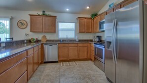 A modern kitchen with wooden cabinets, stainless steel appliances, and a granite countertop.