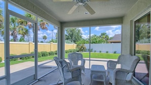 A covered patio with wicker furniture and a ceiling fan.