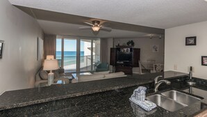 A modern kitchen with a granite countertop, stainless steel sink, and a ceiling fan. - E904 3 Gulf-front pools, Stunning Beach View, Tennis Courts (Panama City Beach)