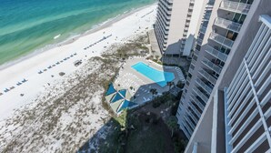 An aerial view of a beachside hotel with a swimming pool, beach umbrellas, and a high-rise building. - E1706 Gulf Front View, 3 Pools, Gated Condo (Panama City)
