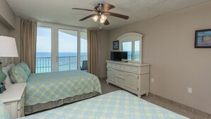 A hotel room with a bed, a dresser, a television, and a balcony with a view of the ocean. - E1706 Gulf Front View, 3 Pools, Gated Condo (Panama City)
