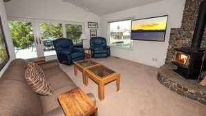 Una sala de estar con chimenea de piedra, un sofá, dos sillones y una mesa de centro.