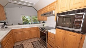 Una cocina con armarios de madera, un microondas de acero inoxidable y una estufa.