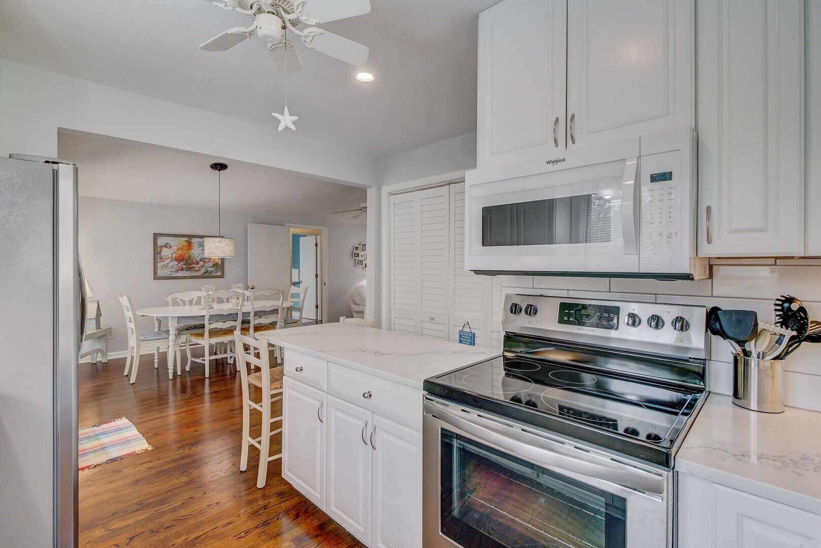 A modern kitchen with white cabinets, a stainless steel stove, and a microwave.