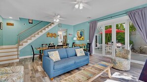 A spacious living room with a blue sofa, a wooden coffee table, and a staircase leading to an upper floor. - **ENDLESS SUMMER @ OLD TOWN** New Villa & Pool + Last Key White Glove Service... (Key West)