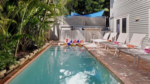 A swimming pool with lounge chairs and inflatable beach balls, surrounded by plants and a wooden fence. - **ENDLESS SUMMER @ OLD TOWN** New Villa & Pool + Last Key White Glove Service... (Key West)