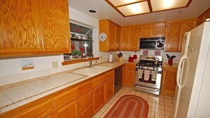 Una cocina con armarios de madera, estufa, microondas y refrigerador.